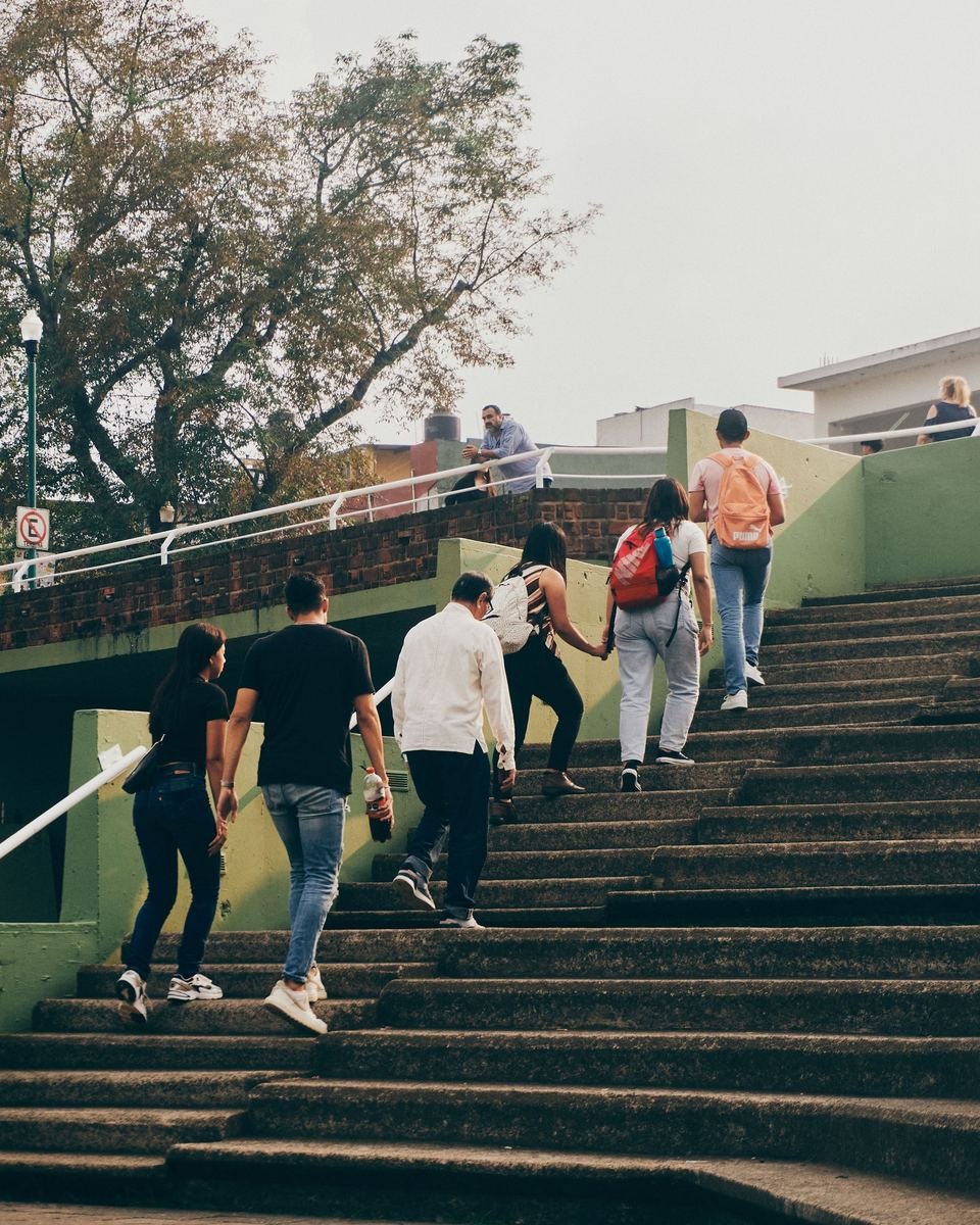 Un grupo de jóvenes, de espaldas, sube una escalera al aire libre en Xalapa en una tarde nublada.